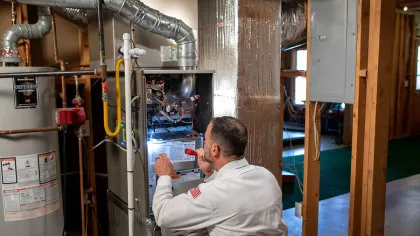 Technician inspecting a heating system in a residential basement with tools and equipment.