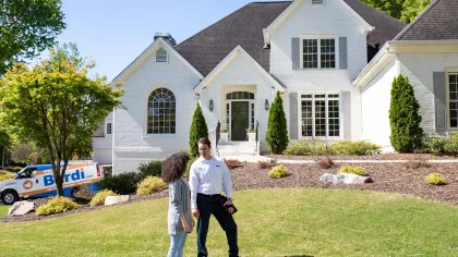 a man and a woman standing in front of a house