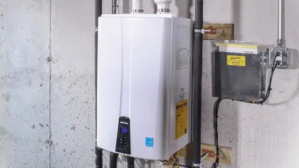 Modern tankless water heater installation with pipes and electrical connections in a basement setting.