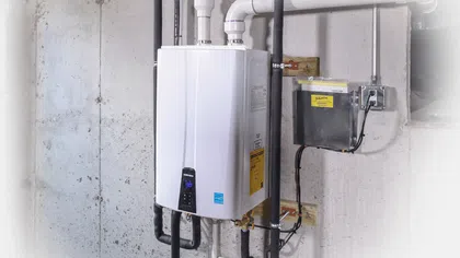 Modern tankless water heater installation with pipes and electrical connections in a basement setting.