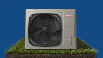 Lennox outdoor air conditioning unit with large fan on a grass patch against blue background