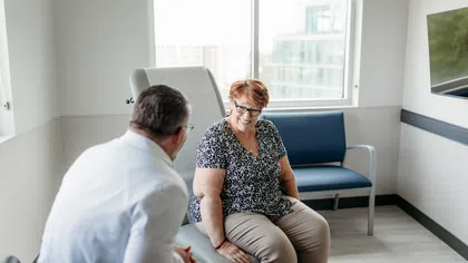 Senior woman smiling and talking with male doctor in a bright medical office during consultation.