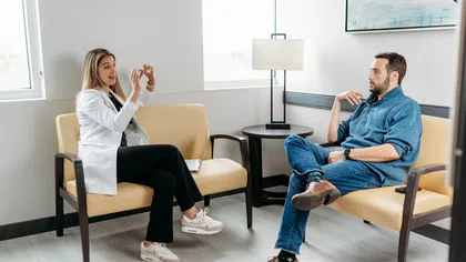 Female doctor in white coat discussing with male patient in casual clothes in a bright medical office