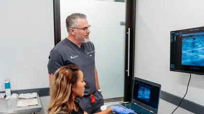 Medical professionals analyzing ultrasound images on a laptop and monitor during a diagnostic session.