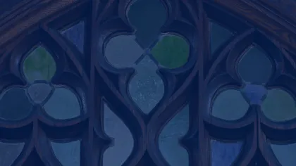 Close-up of stained glass window with blue and green glass panes in dark wooden frame with Gothic design