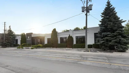 Modern single-story office building with large windows, surrounded by trees and clear skies at sunrise.
