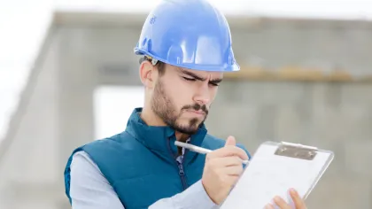 a man wearing a hard hat and holding a piece of paper