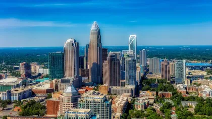 Aerial view of a modern city skyline with tall skyscrapers, dense buildings, and clear blue sky.
