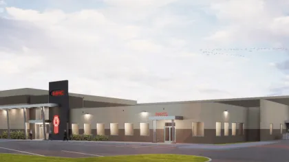 Modern industrial building with MHC and Parts signage at dusk under a partly cloudy sky with birds flying overhead.