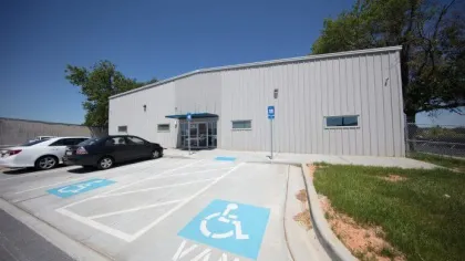 Metal building with accessible van parking spaces and a small entrance canopy under a clear blue sky.