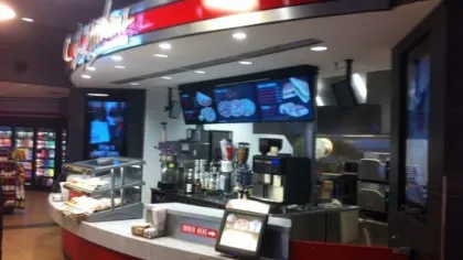 Interior of a modern pizza counter with digital menu screens and ready-to-serve food displays.
