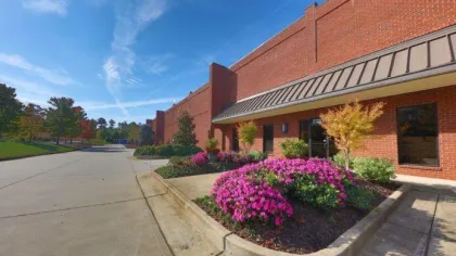 Red brick commercial building with landscaped flower beds and clear blue sky on a sunny day