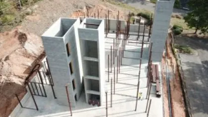 Aerial view of a multi-story concrete building under construction with steel reinforcements and unfinished walls.