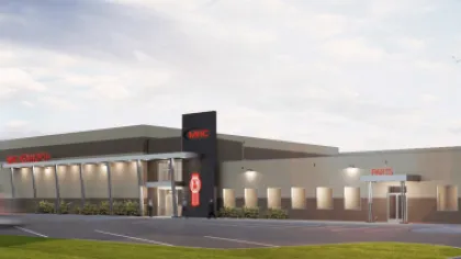 Modern Kenworth building exterior at dusk with clear sky and well-lit entrance and parking area