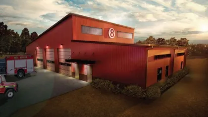 Red fire rescue station 8 building at sunset with fire trucks parked outside in a rural setting.