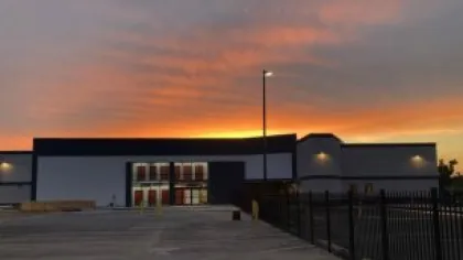 Modern building with large windows and fence at sunset with vibrant orange and purple sky colors.