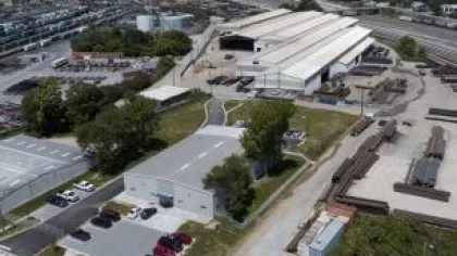 Aerial view of an industrial factory complex with warehouses, parking lots, and storage areas under clear skies