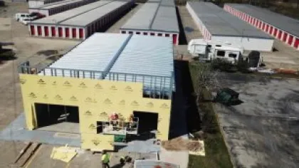 Aerial view of a construction site with workers building a storage unit facility with rows of completed storage units.