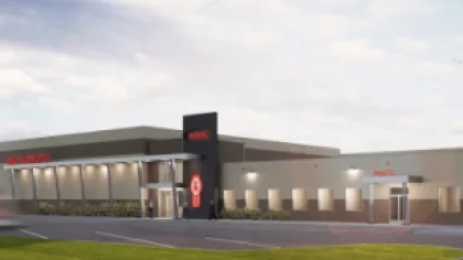 Modern AMC movie theater building exterior with wide entrance and parking area under a partly cloudy sky