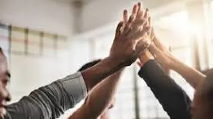 Group of people giving a collective high five in a bright office setting symbolizing teamwork and success.