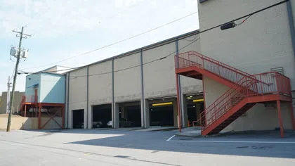 Urban commercial building with multiple garage bays and red exterior staircases under clear sky.