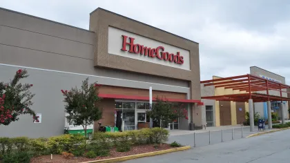 Exterior view of a HomeGoods store with clear signage and landscaped entrance under a cloudy sky.