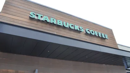 Exterior view of a Starbucks Coffee shop with wooden paneling and green signage on a clear day