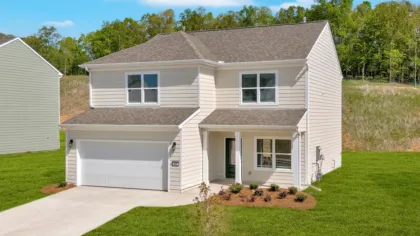 Two-story white house with a gray roof, attached garage, front porch, and green lawn under clear sky.