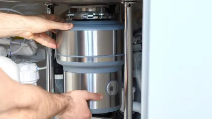a plumbing technician repairing a garbage disposal
