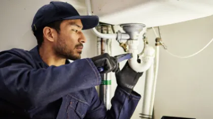a plumber fixing a pipe under a sink