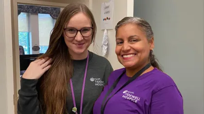 Two smiling hospice workers wearing Tidewell Hospice shirts and lanyards in an office setting