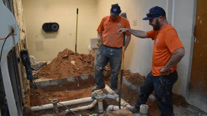 Estes Services plumbers repairing exposed sewer pipes during an under-slab plumbing replacement.