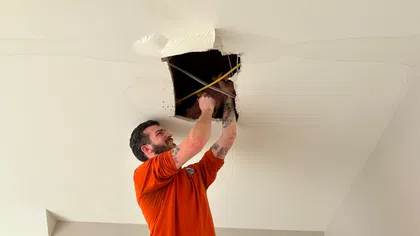 Estes Services plumber inspecting a ceiling water leak during residential leak repair service.