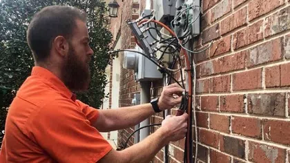 Estes Services Technician working on electrical wiring outside a brick building, ensuring proper connections and installation.