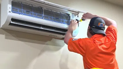 Estes Services technician installing a wall-mounted ductless mini-split system in a residential home.