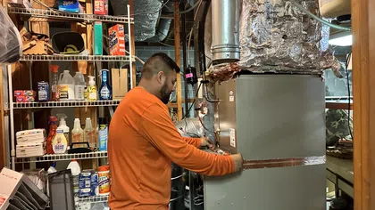 Estes Services technician installing a residential heating system and connecting it to the home’s ductwork.
