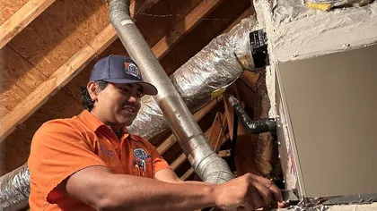 Estes Services HVAC technician installing heating equipment inside a residential attic