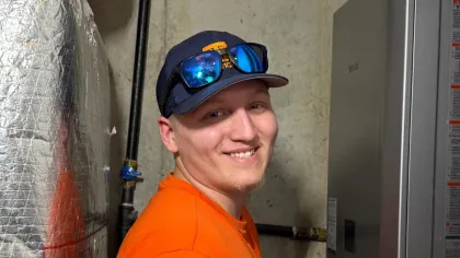 Smiling Estes Services Plumber Providing Maintenance for Tankless Water Heaters