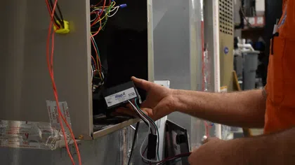 Estes Services Technician installing wiring inside a metal HVAC unit with multiple colored wires.