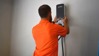 Estes Services Electrician installing a JuiceBox EV charger on a wall, demonstrating electric vehicle charging technology.