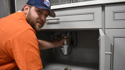 Estes Services plumber servicing an under-sink drain during residential drain service.