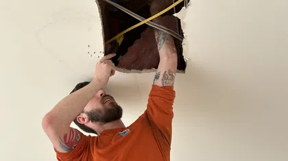 Estes Services plumber inspecting a ceiling water leak during residential leak repair service.
