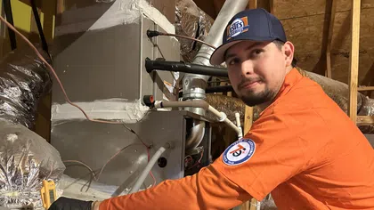 Estes Services HVAC technician performing heating repair on attic equipment inside a home