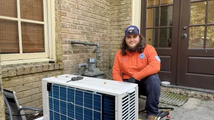 Estes Services technician beside an outdoor ductless mini-split unit during residential HVAC service.