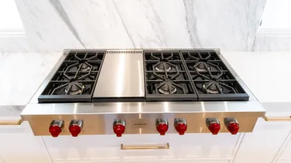 High-end Wolf gas cooktop with five burners and stainless steel finish on a marble countertop.