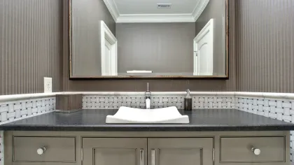 Modern bathroom vanity with a white vessel sink, gray countertop, large mirror, and patterned tile backsplash