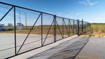A black chain-link fence surrounds a vast open area under a clear blue sky.