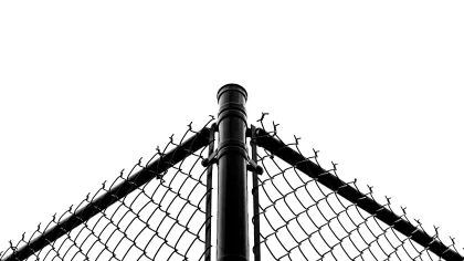 Black chain-link fence corner against a white background, showcasing metal structure and sharp lines.
