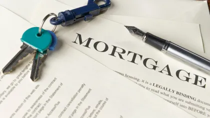 Mortgage documentation with keys and a fountain pen on a table, representing home buying and financing.