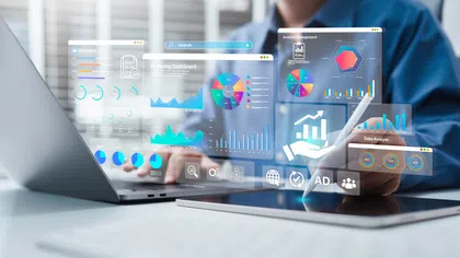 Person working on laptop and tablet with digital data analytics dashboards and charts holographically displayed